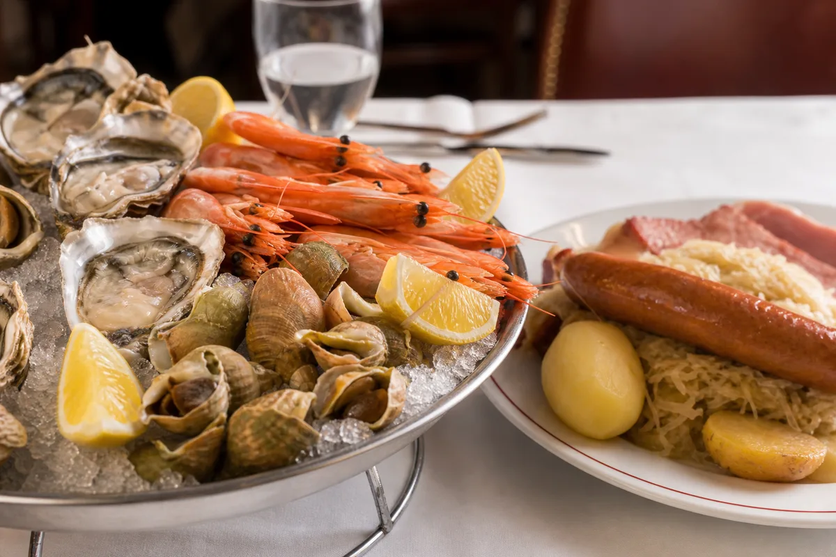 Plateau de fruits de mer sur glace et choucroute garnie servis sur une table de brasserie